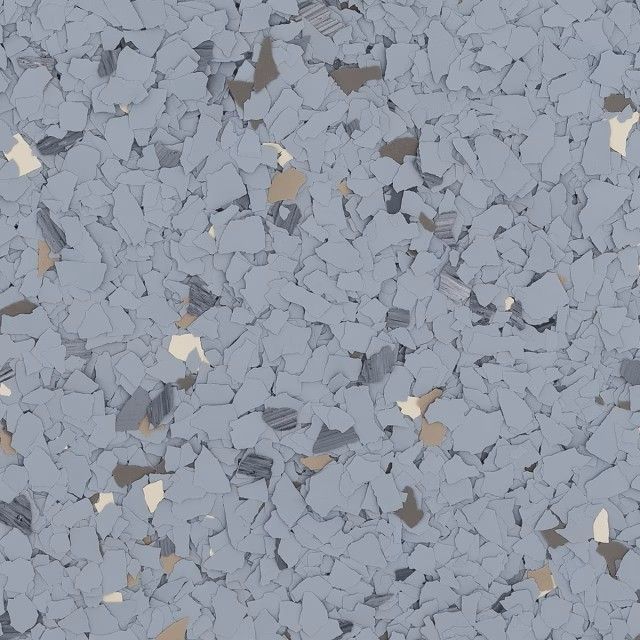 A close-up of a grey, speckled epoxy floor finish with small, irregular chips in shades of light grey, white, and tan.