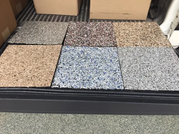 Six square floor tile samples with speckled, textured finishes in shades of gray, brown, tan, and blue.