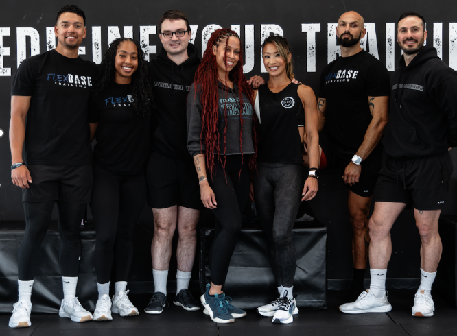 Group of people in fitness attire posing in a gym, with a