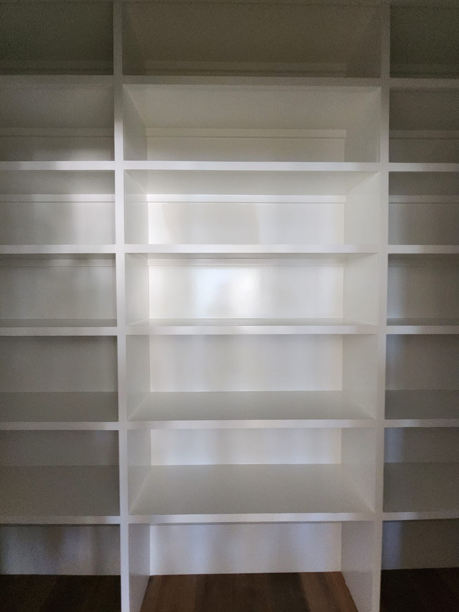 a room filled with lots of white shelves and a wooden floor