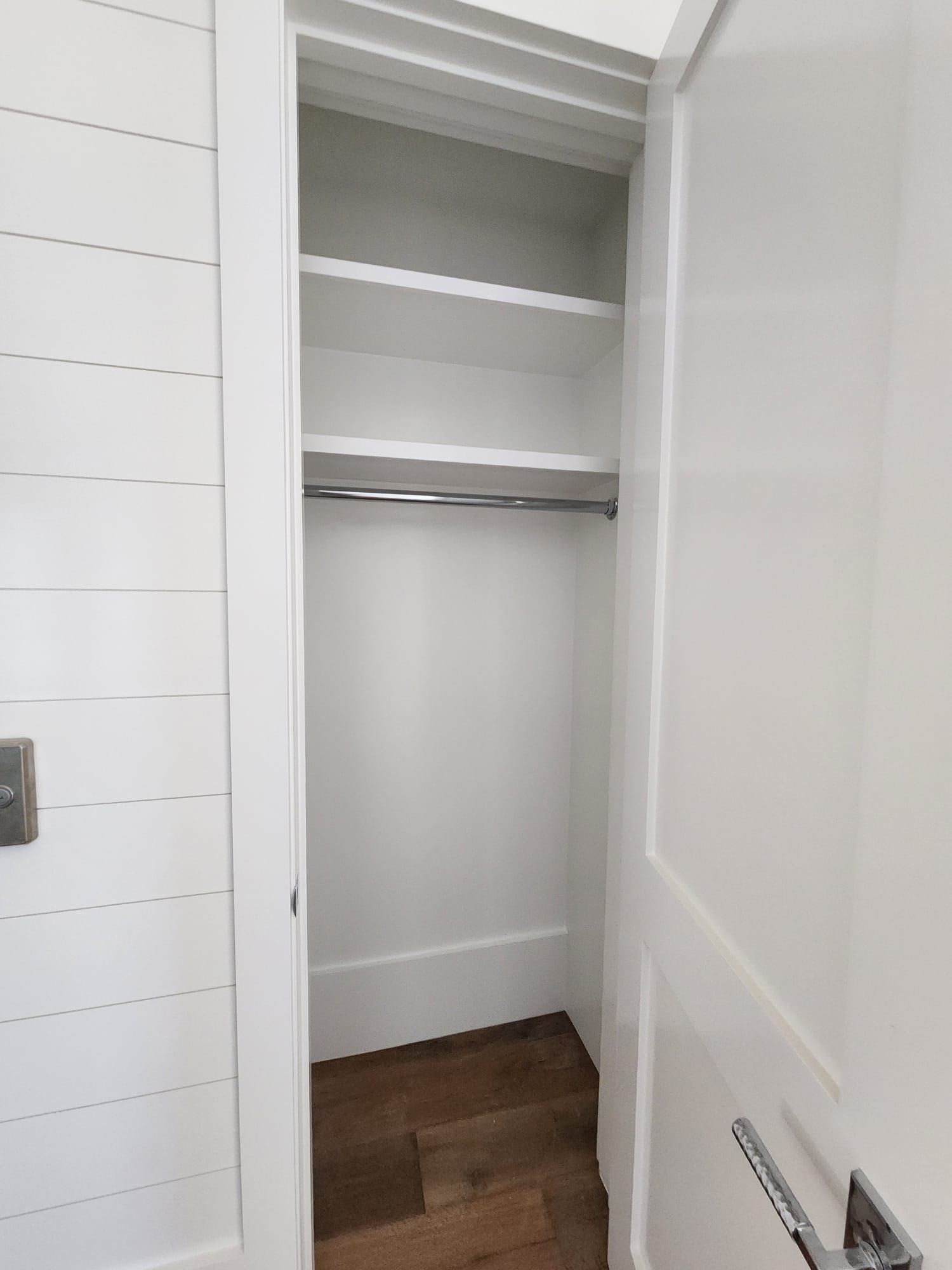 a closet with a door open and shelves and a hanger