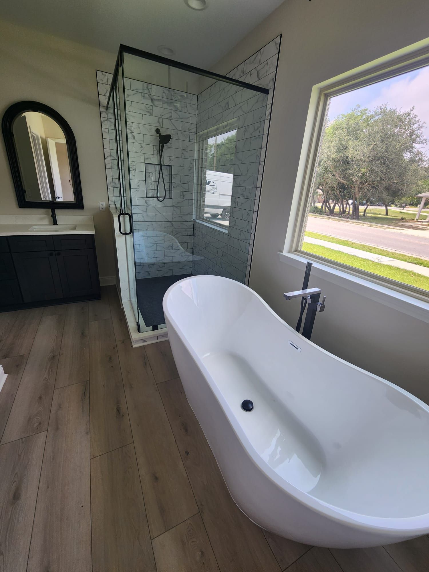 a bathroom with a tub, shower, sink and mirror