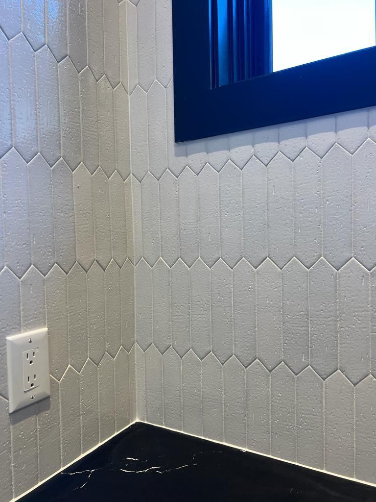 a bathroom with white tiles and a black counter top