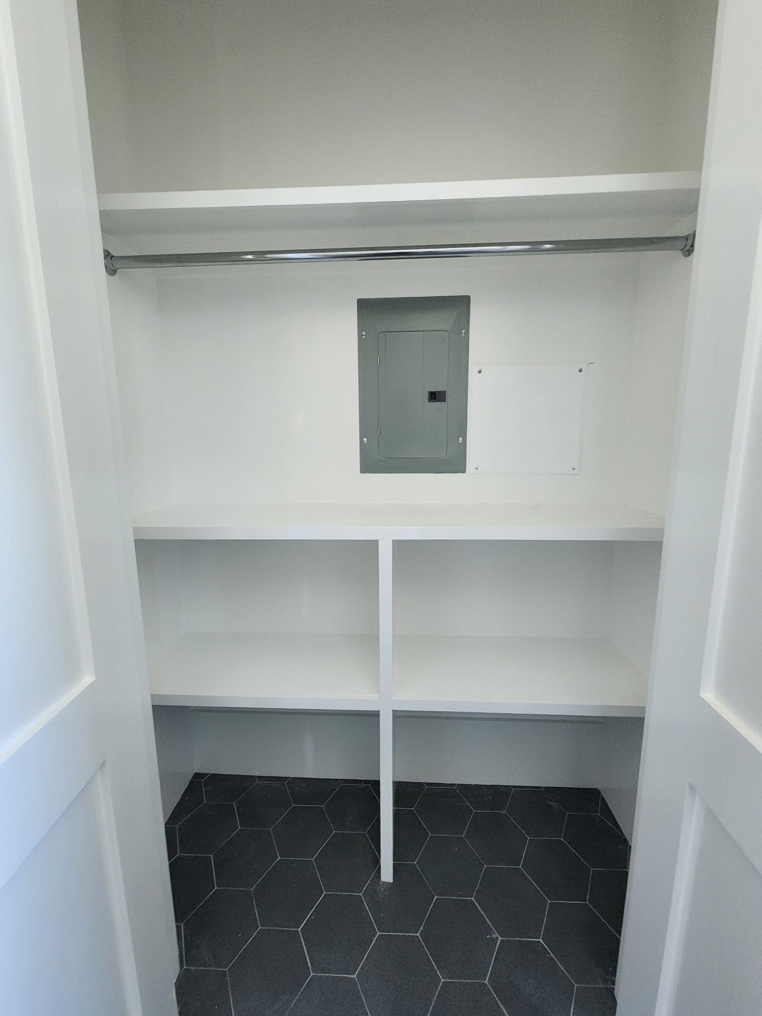 a closet with white shelves and a black tile floor