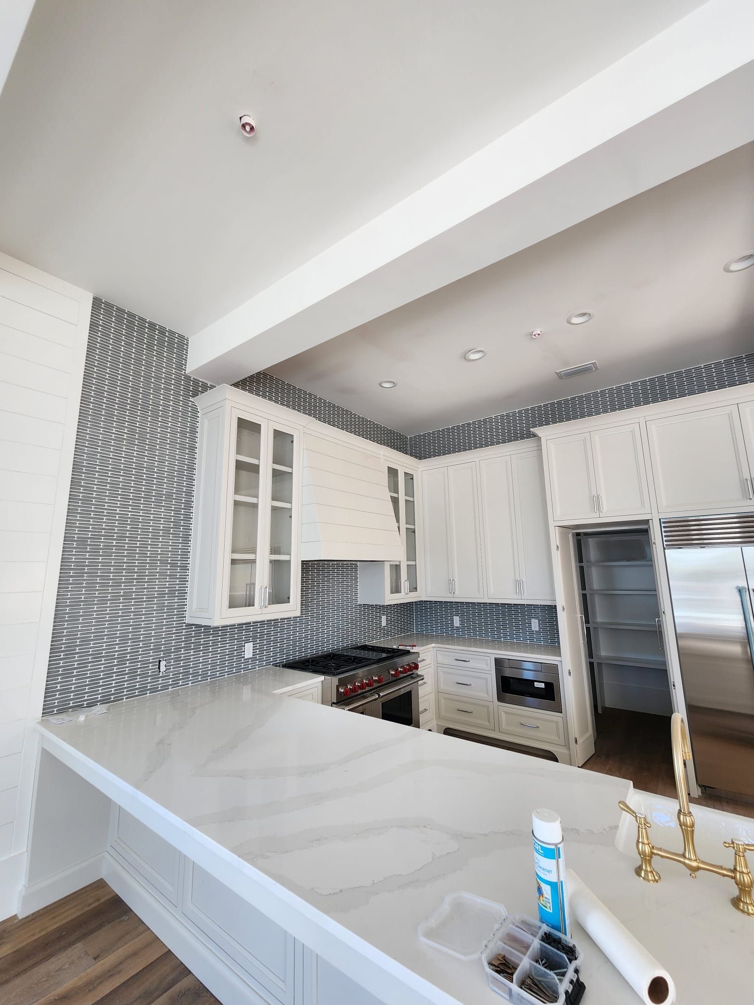 a kitchen with white cabinets, stainless steel appliances, marble countertops, and a large island