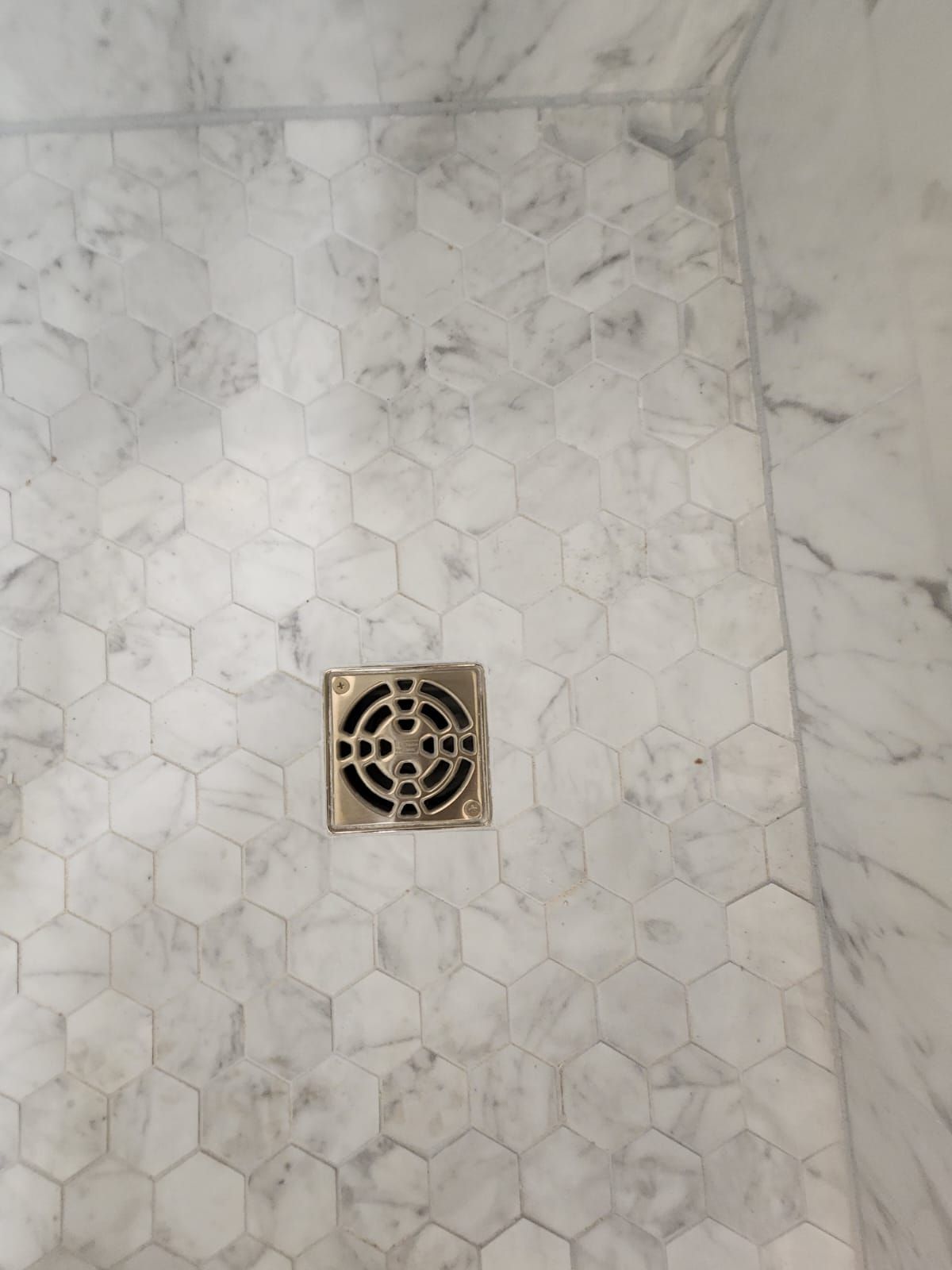 a shower drain on a marble floor in a bathroom