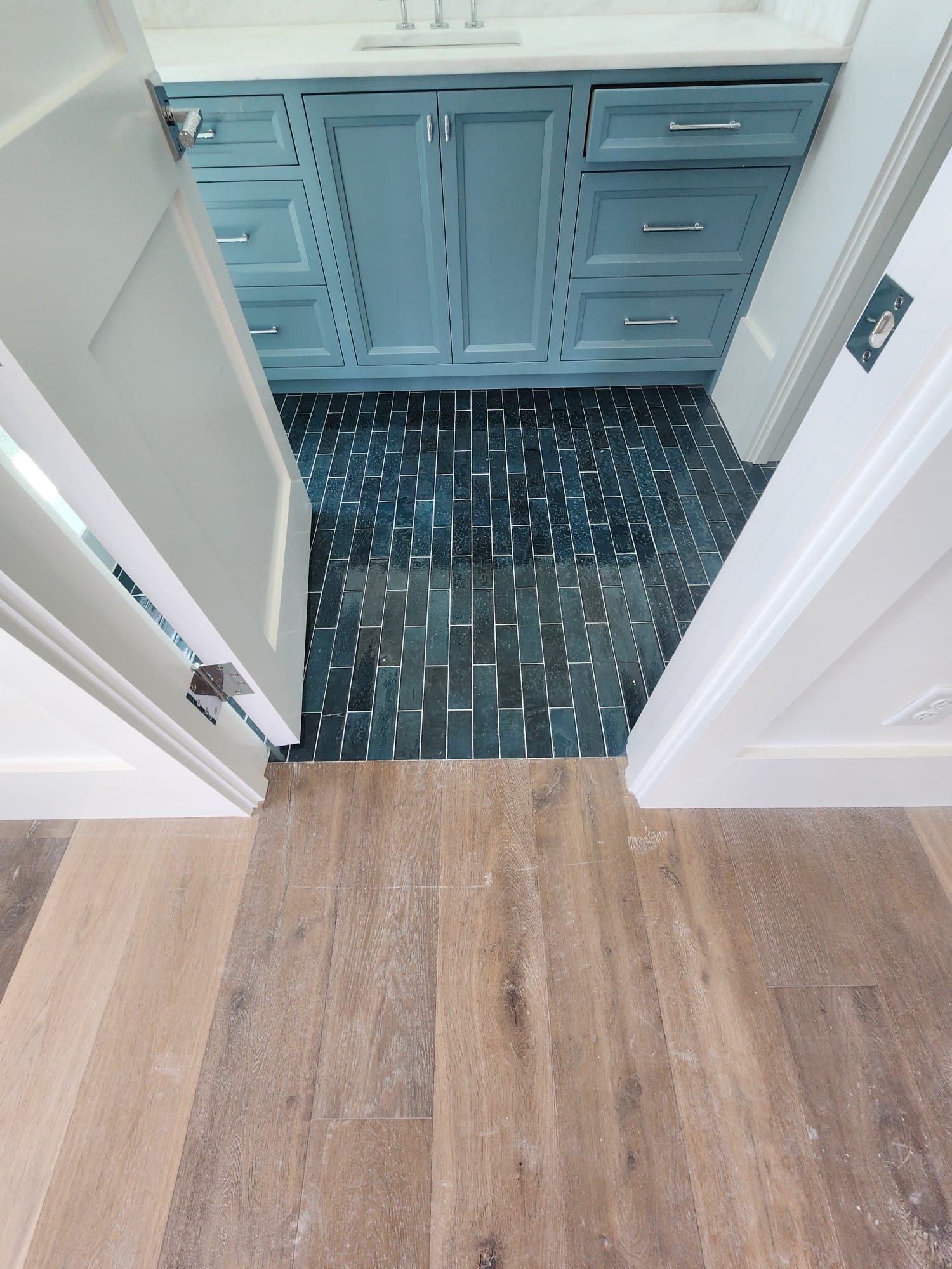 a bathroom with a wooden floor and blue cabinets