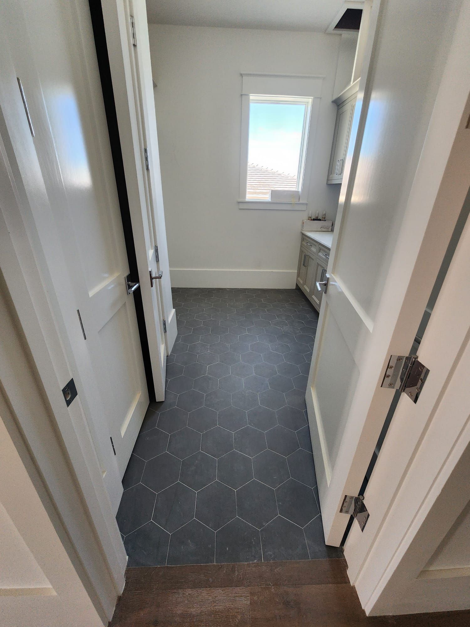 a laundry room with black tile floors and white walls