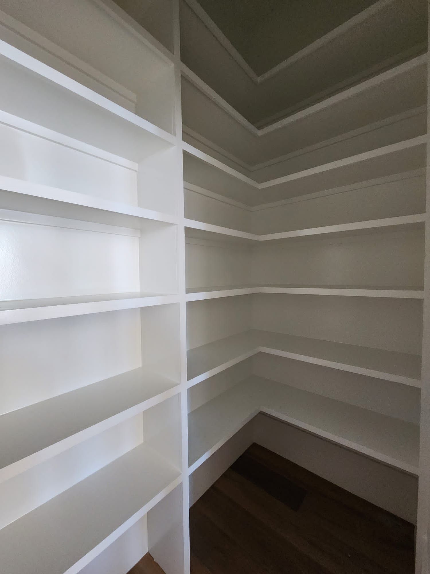 a pantry with lots of shelves and a wooden floor