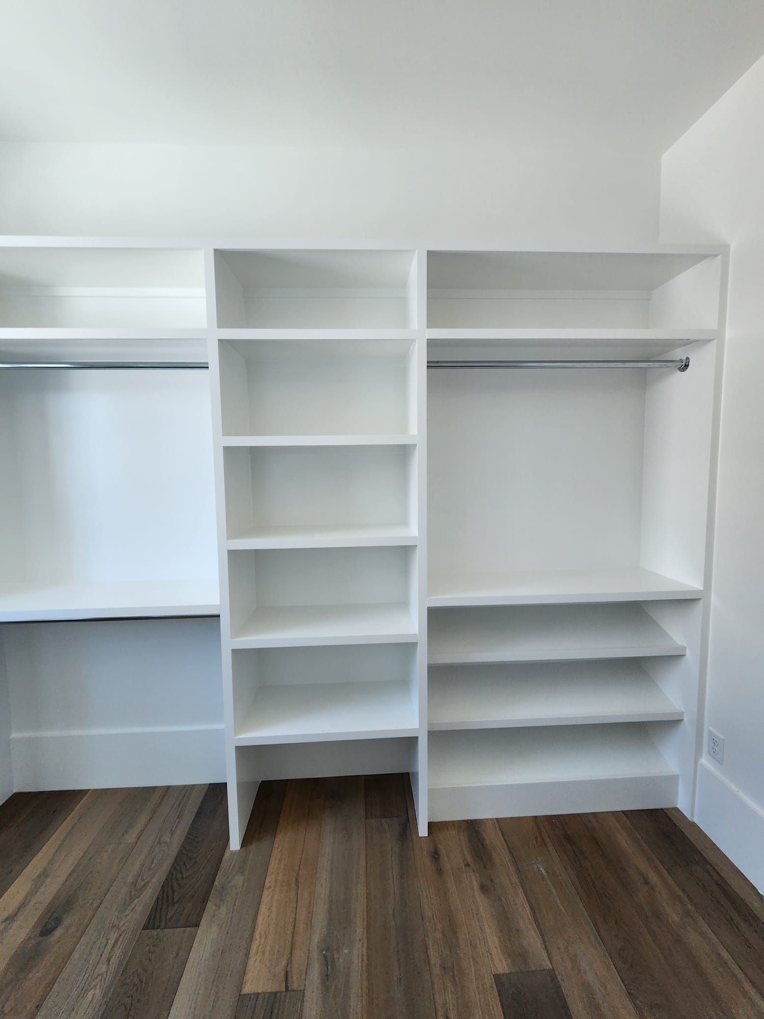 a walk-in closet with white shelves and a wooden floor