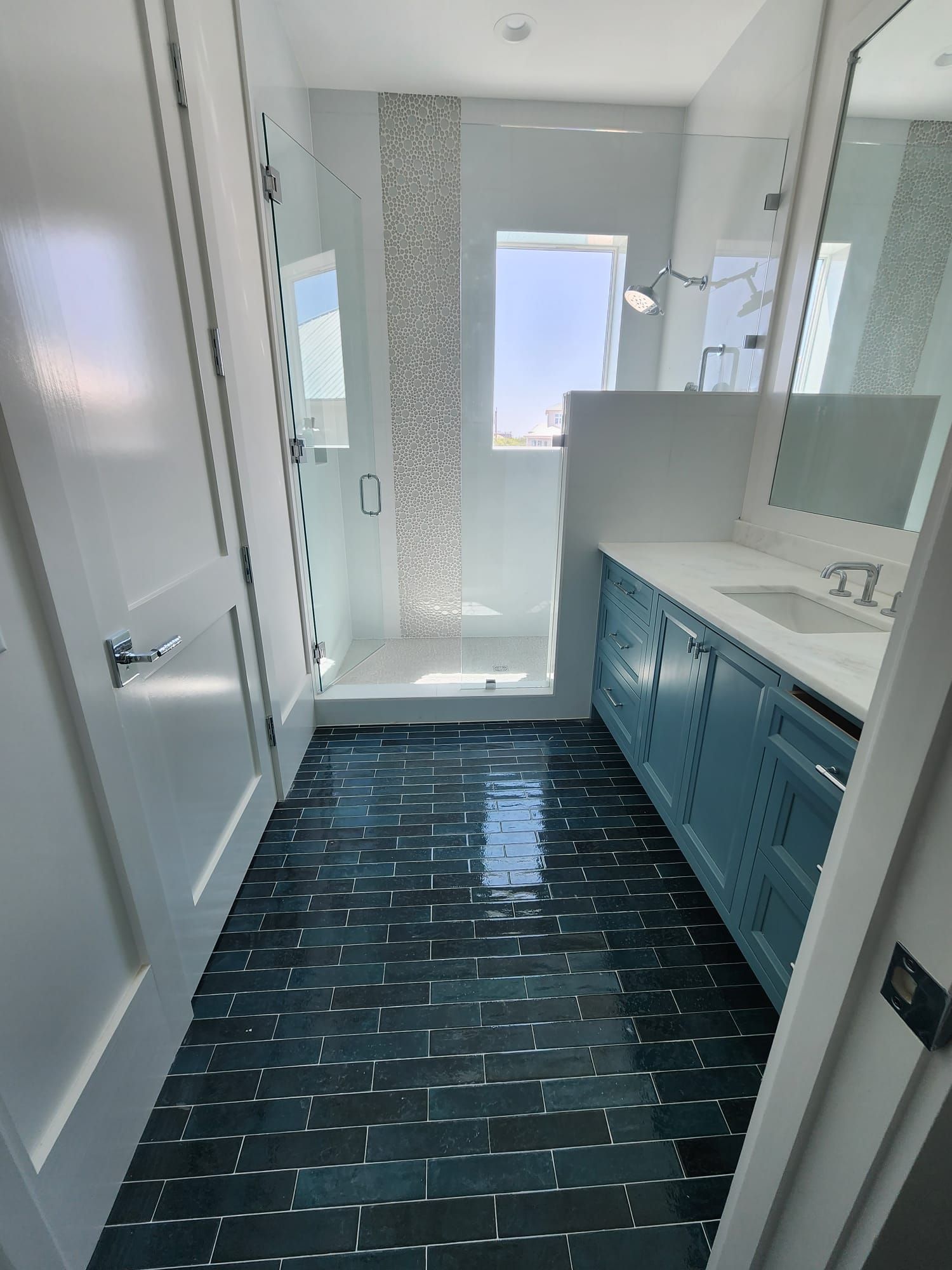 a bathroom with blue cabinets and a walk-in shower