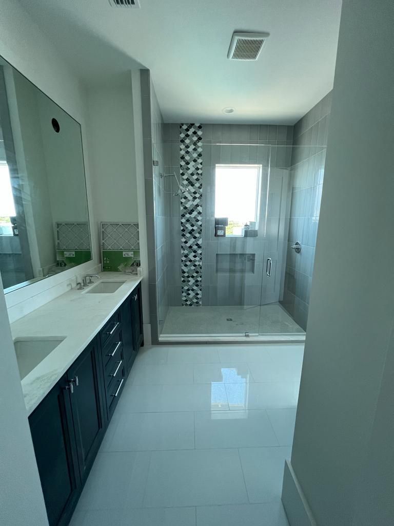 a bathroom with a sink, mirror, and walk-in shower