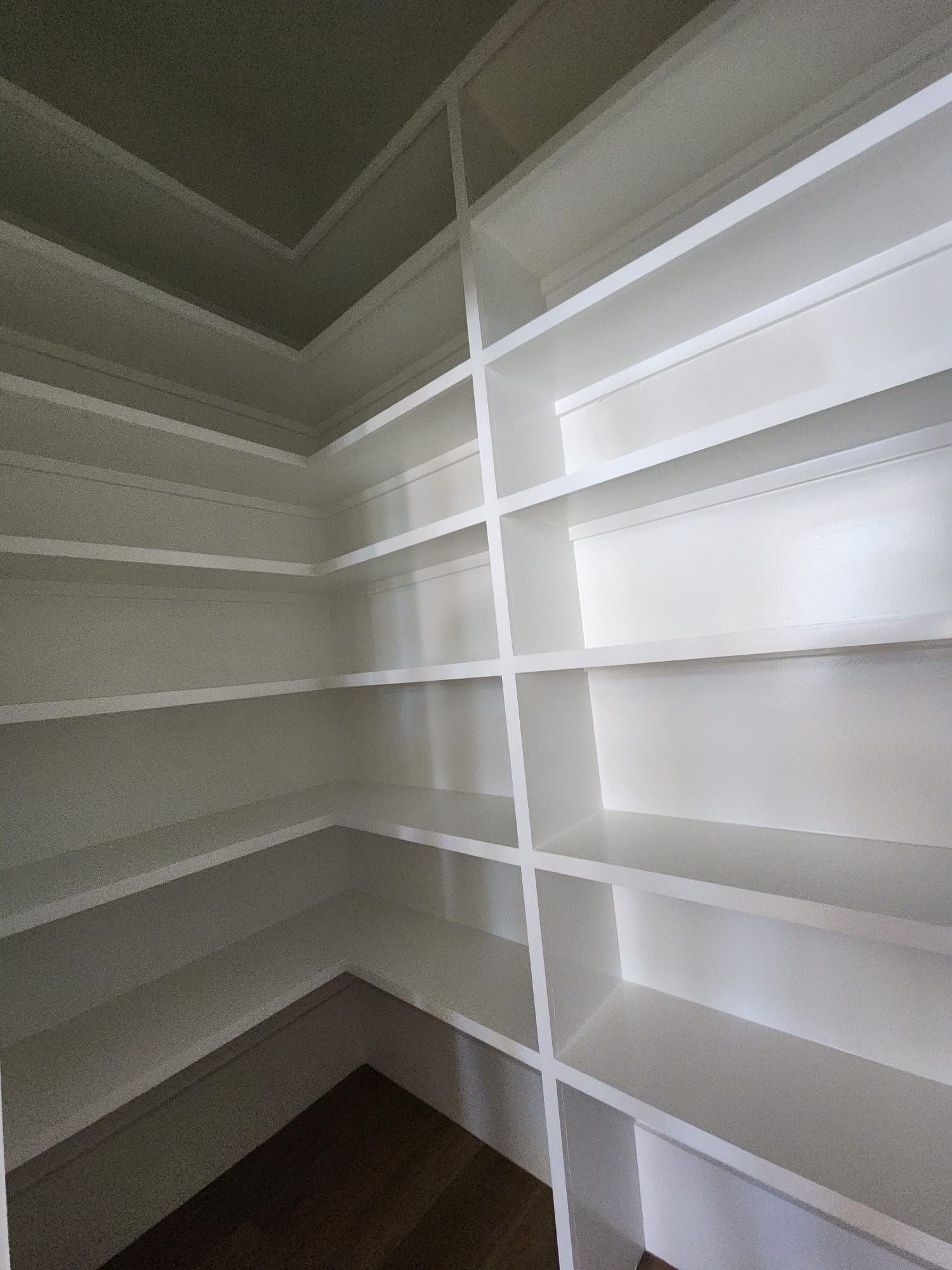 a closet with lots of shelves and a wooden floor