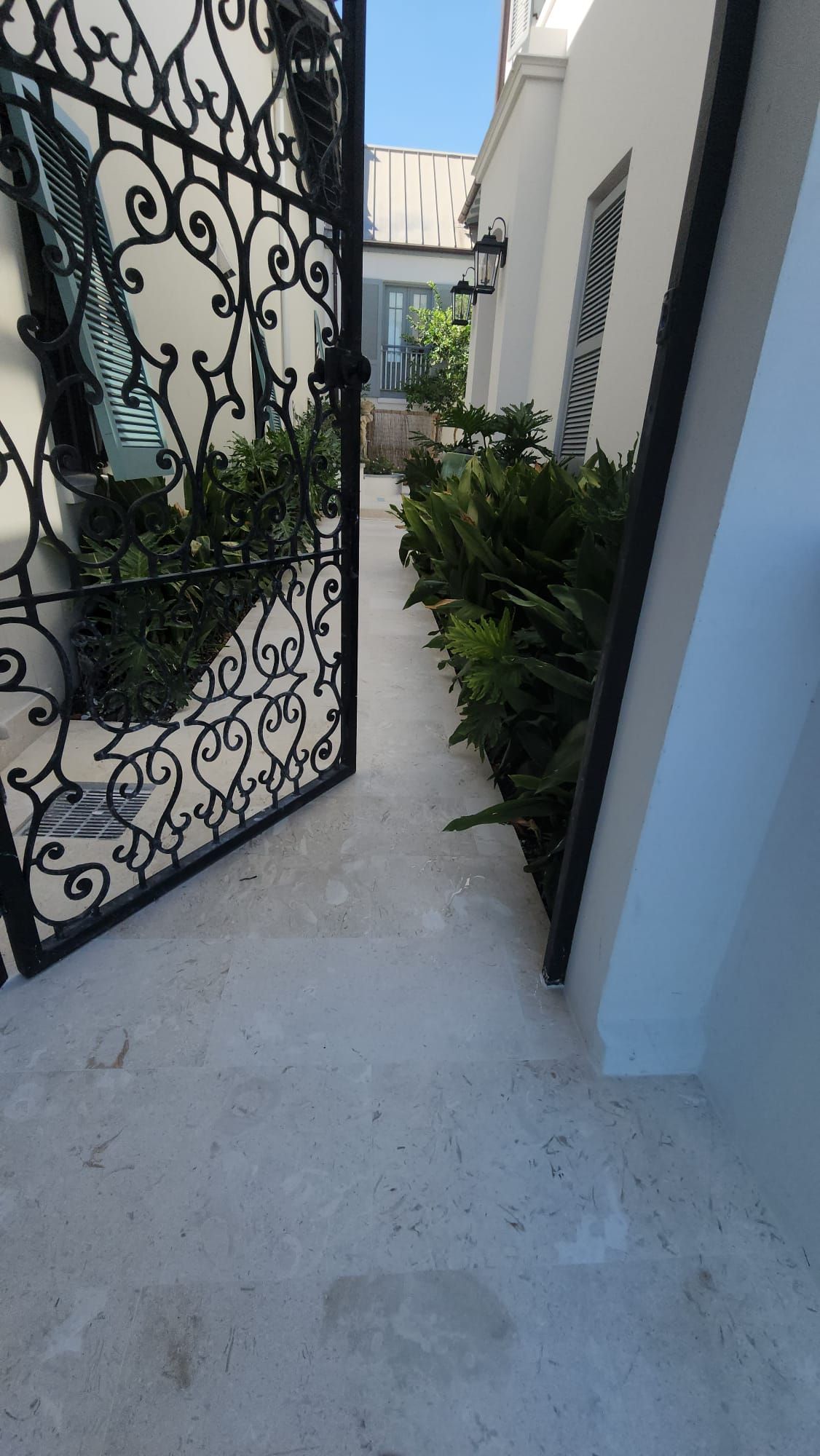 a wrought iron gate is open to a walkway leading to a house