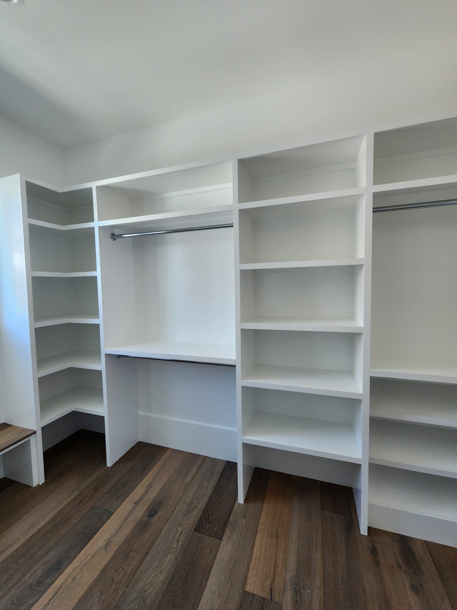 a walk-in closet with lots of shelves and a wooden floor
