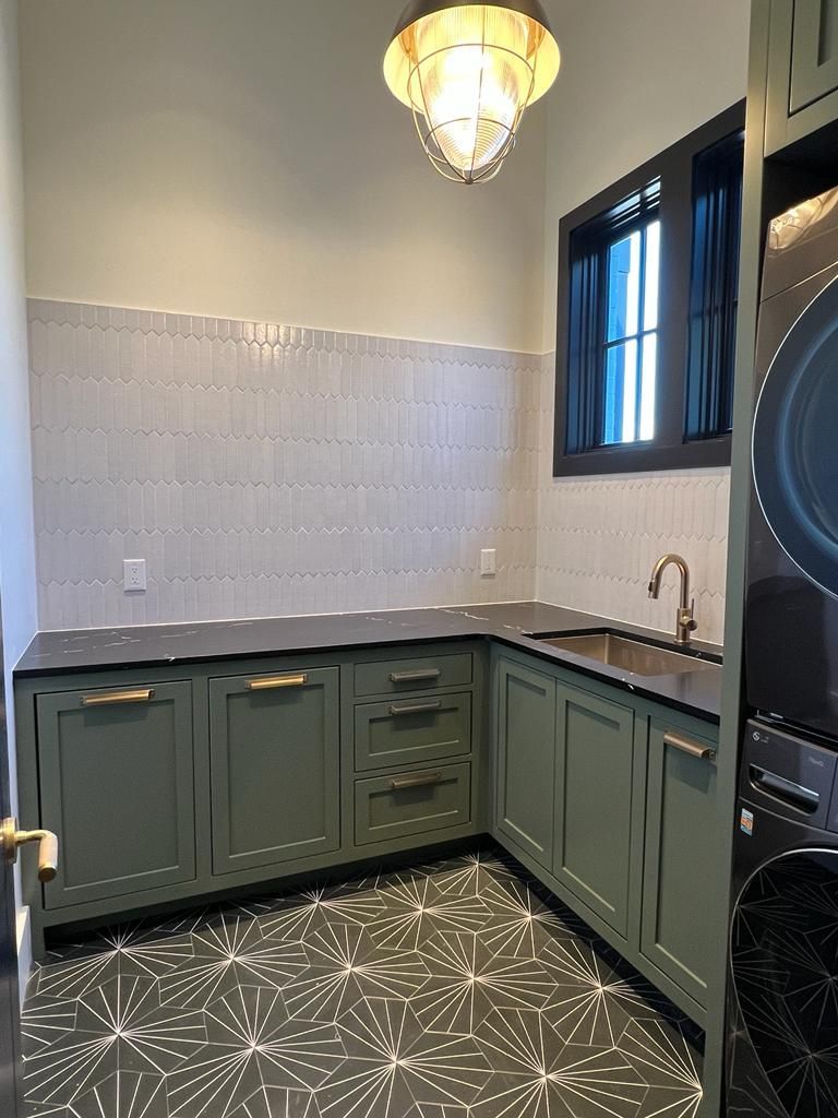 a laundry room with green cabinets, a washer and dryer, a sink, and a window