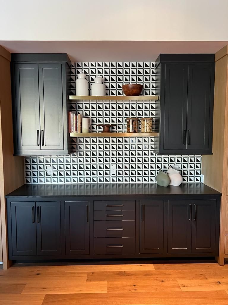 a kitchen with black cabinets and white tiles on the wall