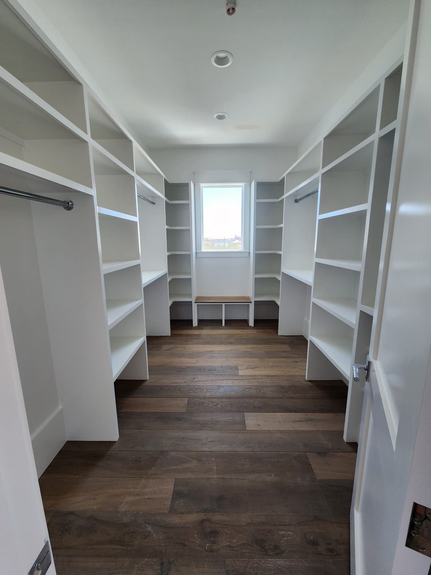 a walk in closet with lots of shelves and a window .