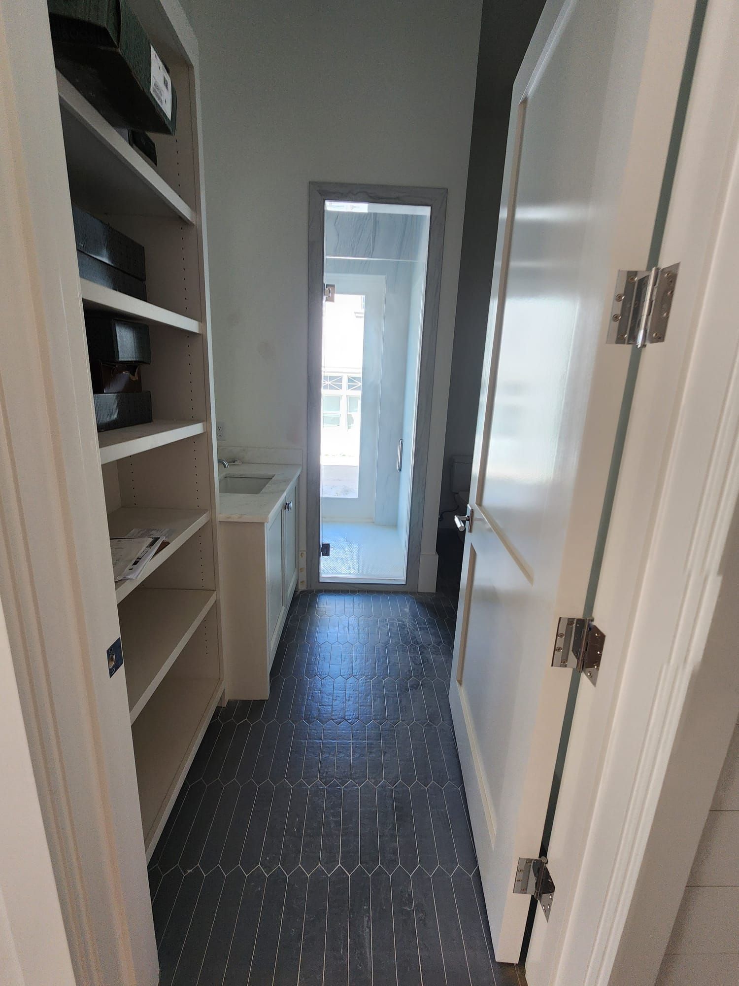 a hallway with shelves and a door leading to a bathroom