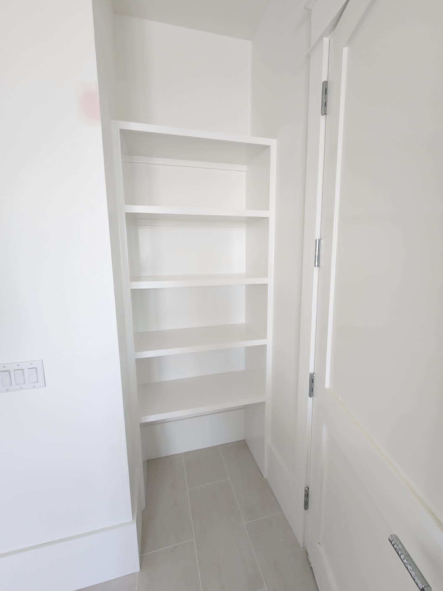 a white closet with shelves and a door