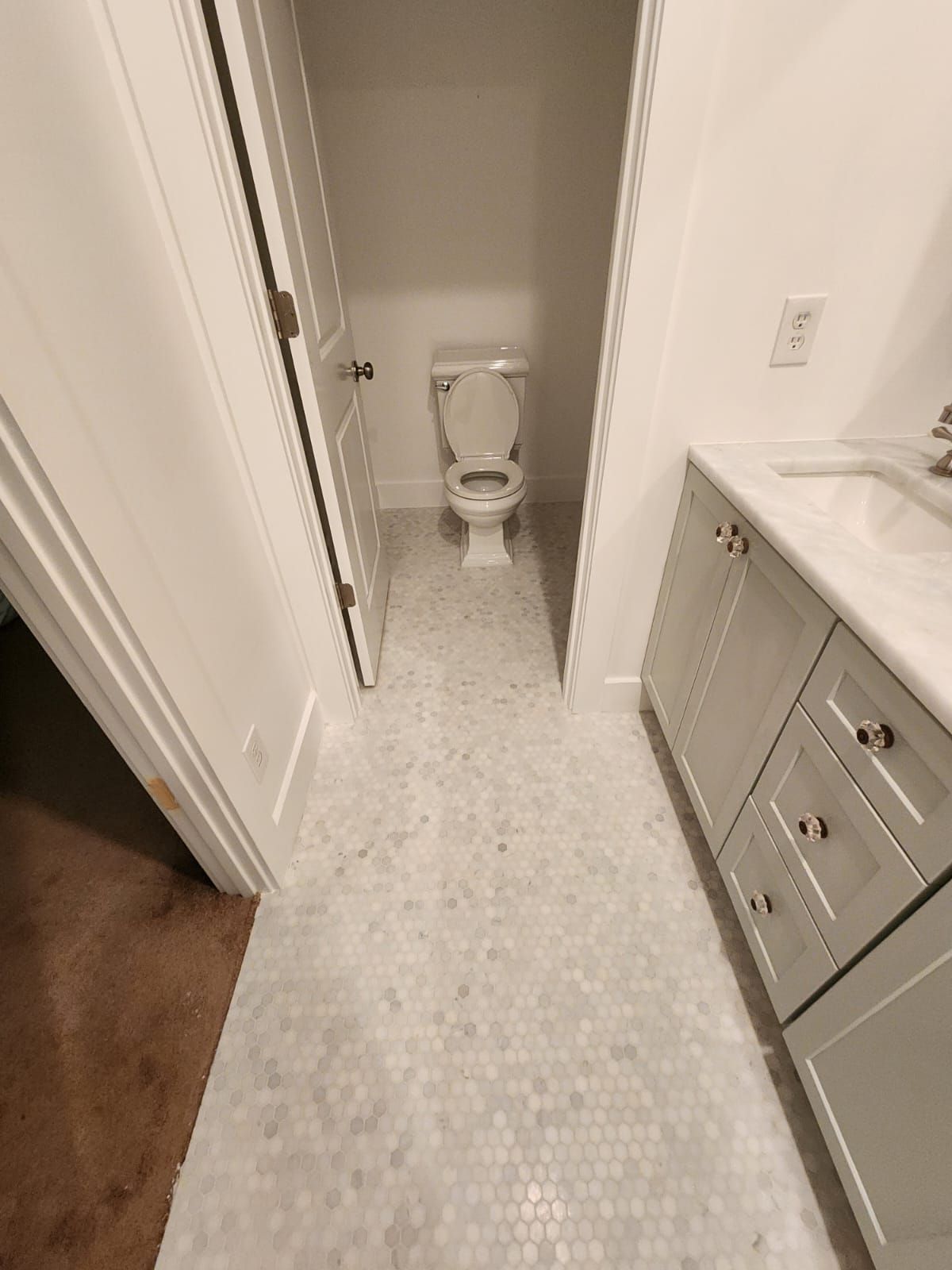 a bathroom with a toilet, sink, and cabinets