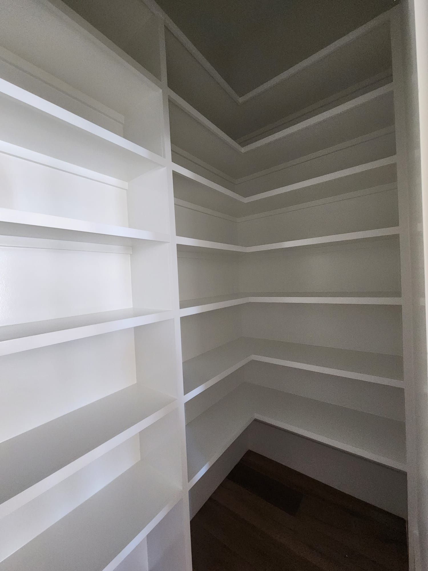 a pantry with lots of shelves and a wooden floor