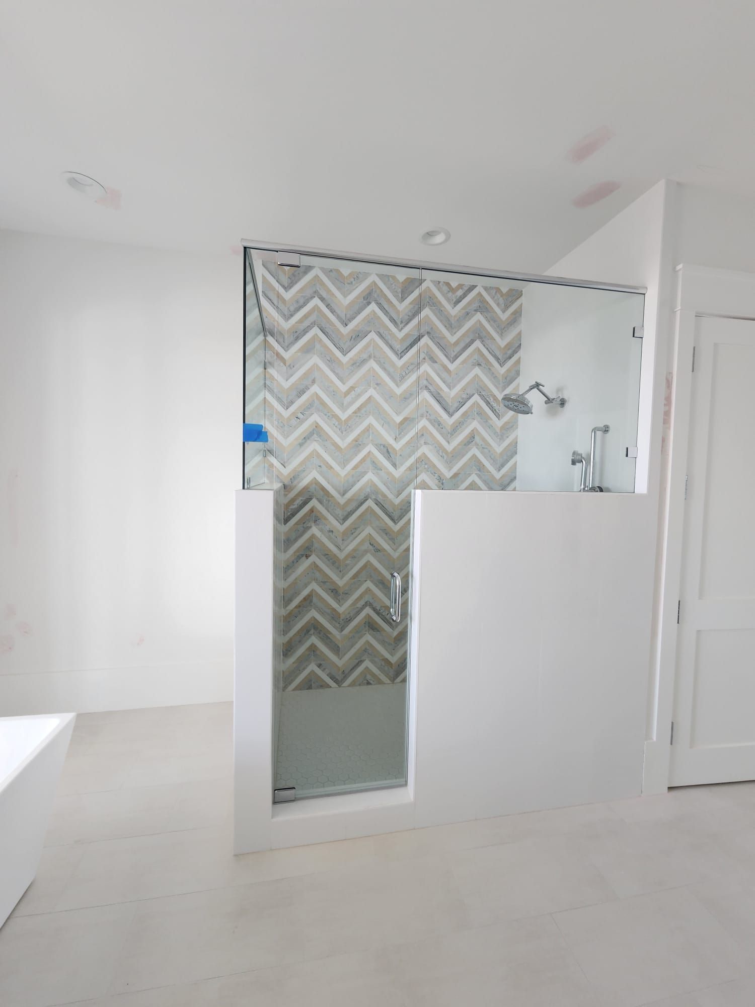 a bathroom with a walk-in shower and a chevron tile wall