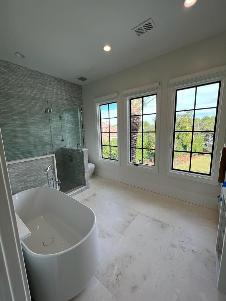 a bathroom with a tub, toilet, shower, and windows