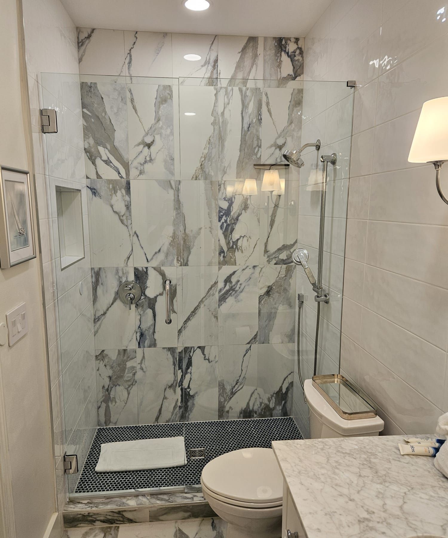 a bathroom with a toilet, sink, and shower with a glass door