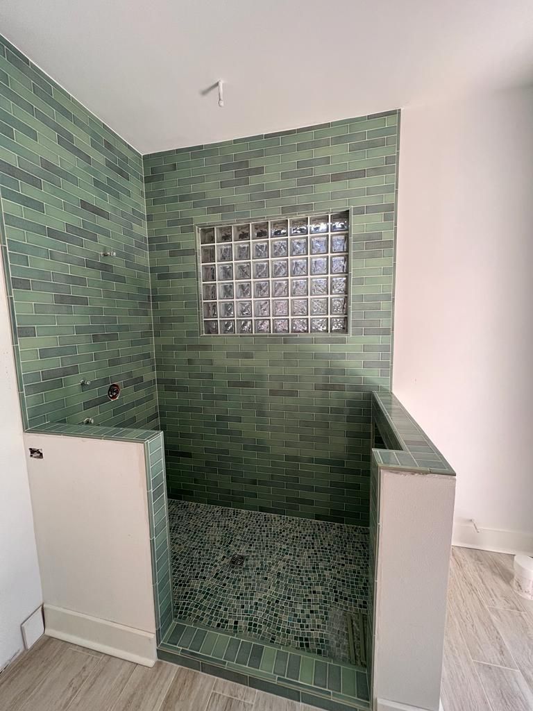 a bathroom with green tiles and a glass block window
