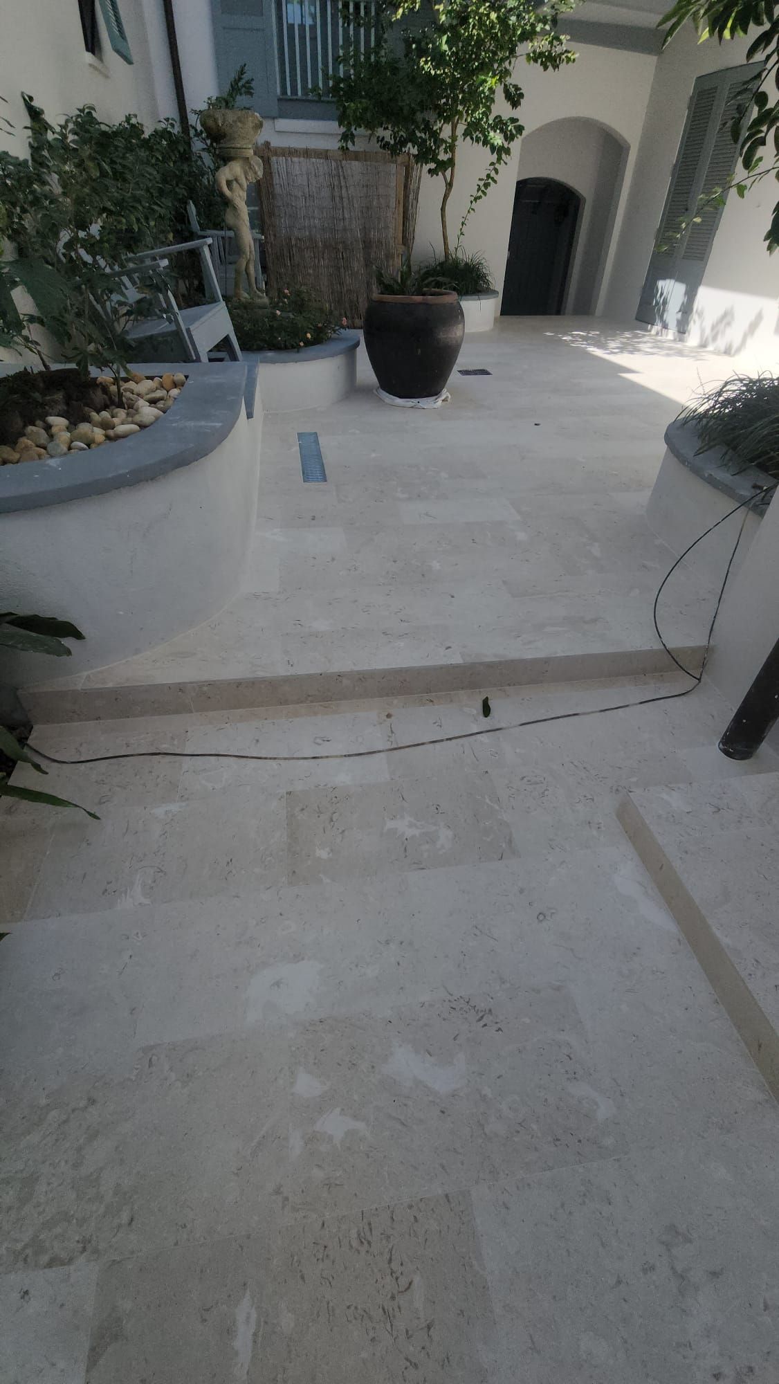 a white tiled floor with potted plants on it in front of a building