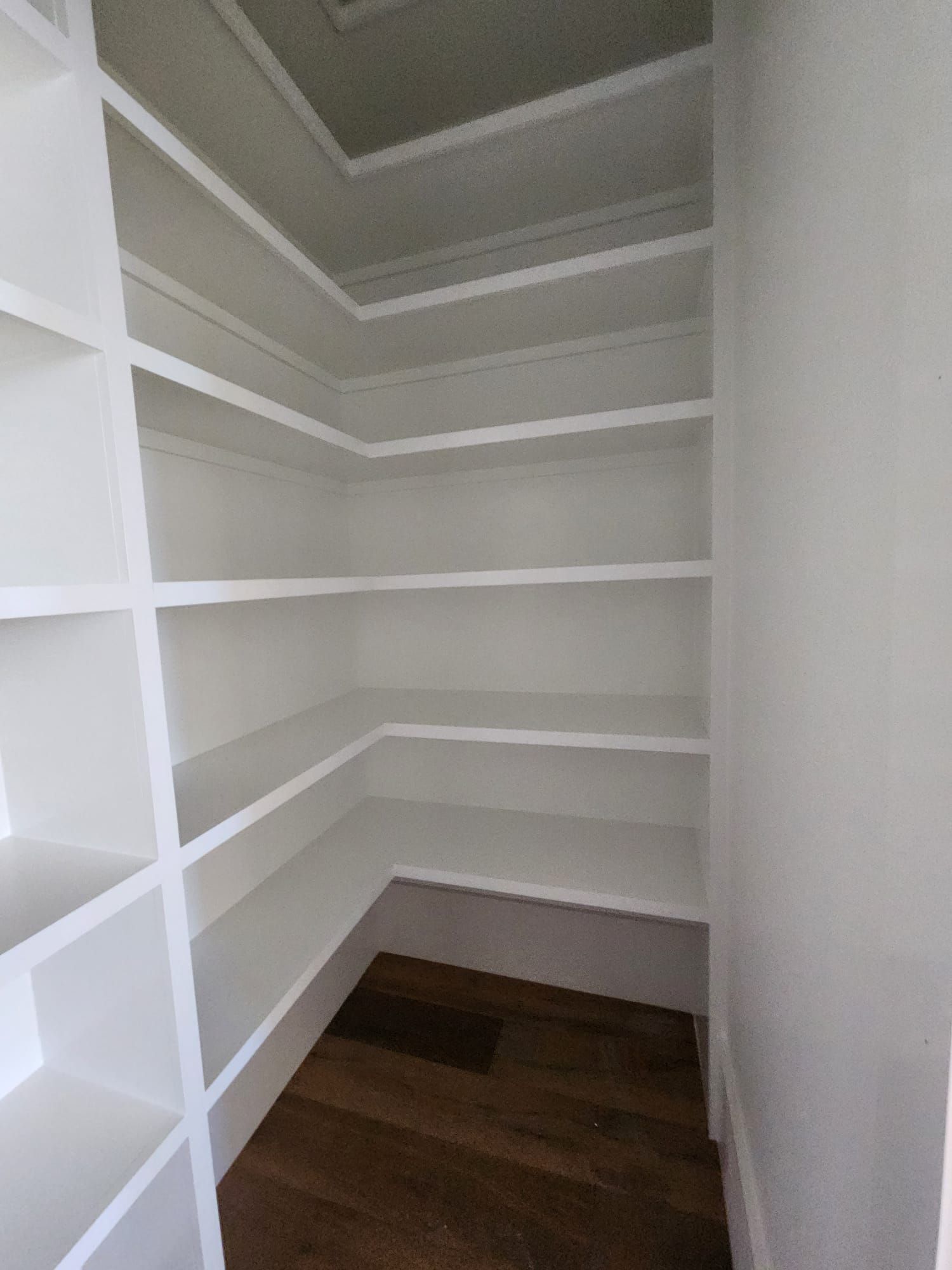 a closet with white shelves and a wooden floor
