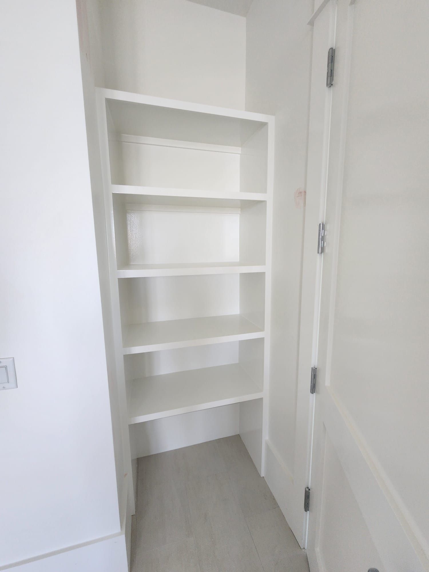 a white closet with shelves and a door in a room