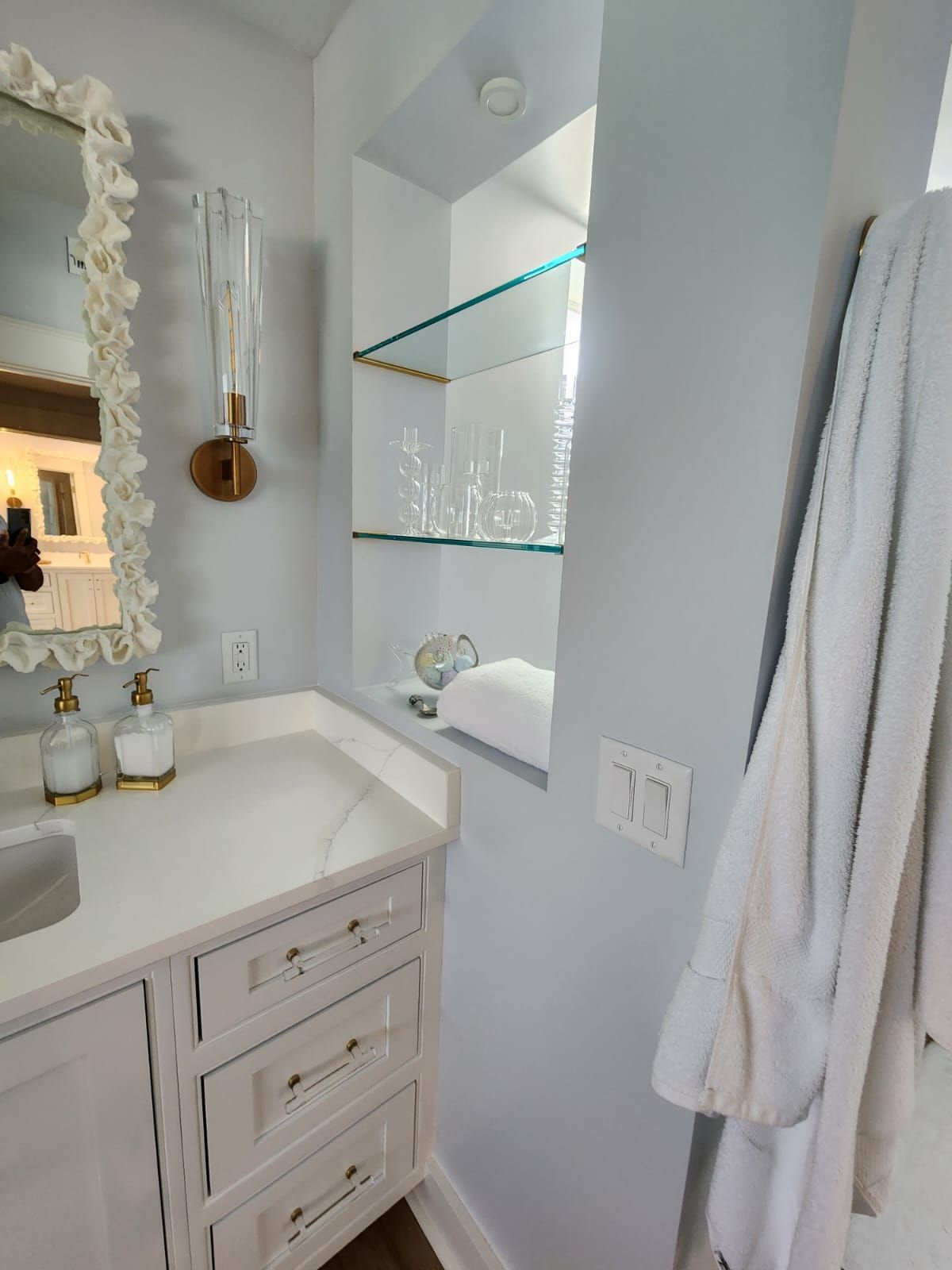 a bathroom with a sink, mirror, and a robe hanging on the wall