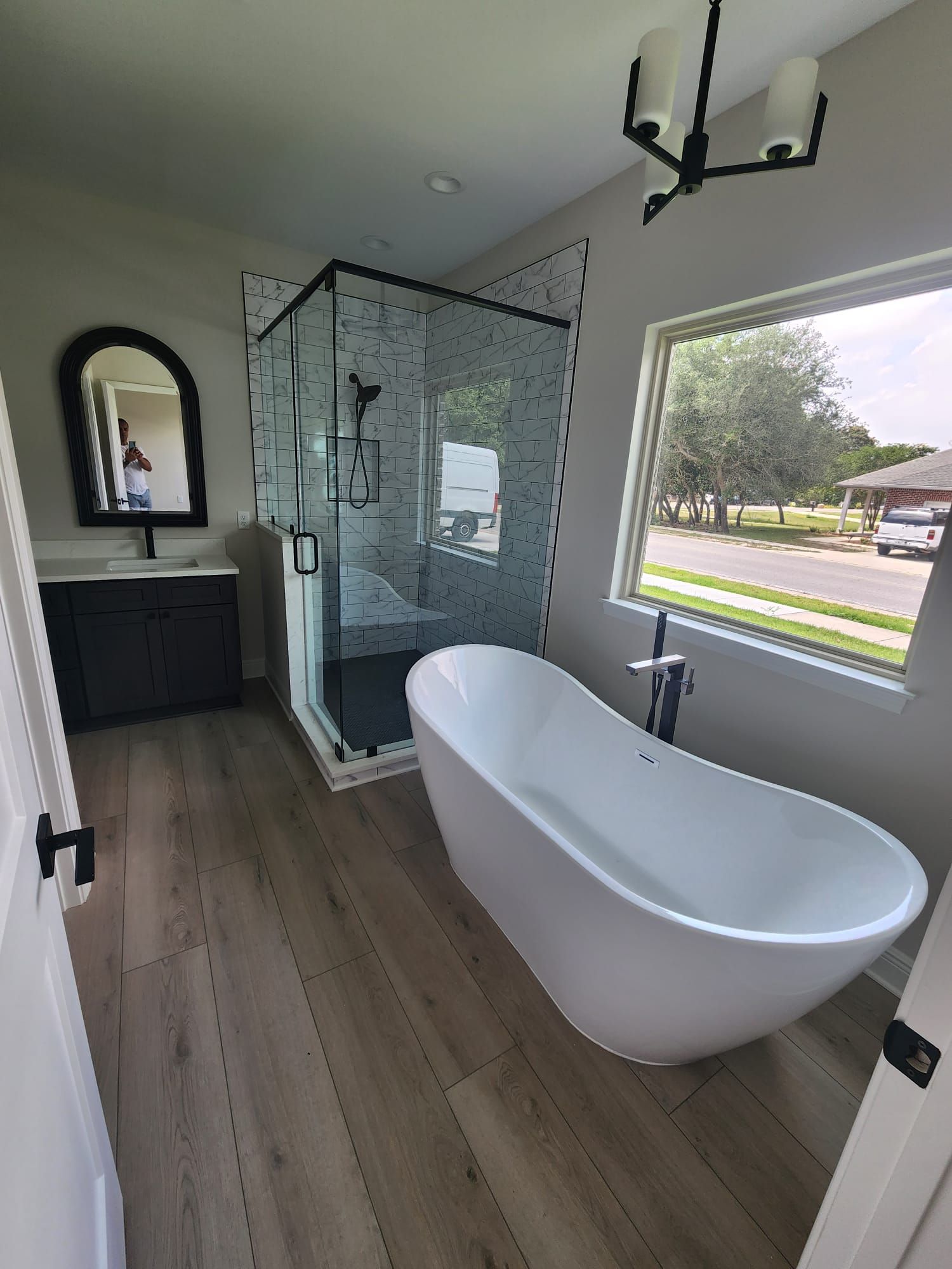 a bathroom with a tub, shower, sink and mirror