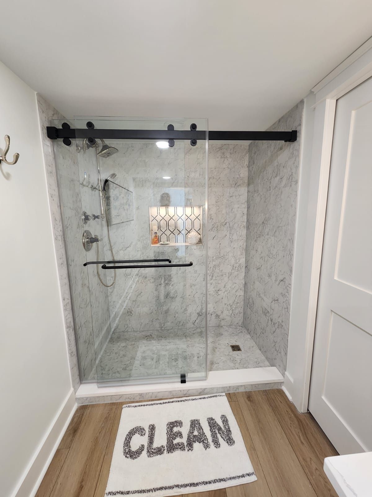 a bathroom with a sliding glass shower door and a rug that says clean