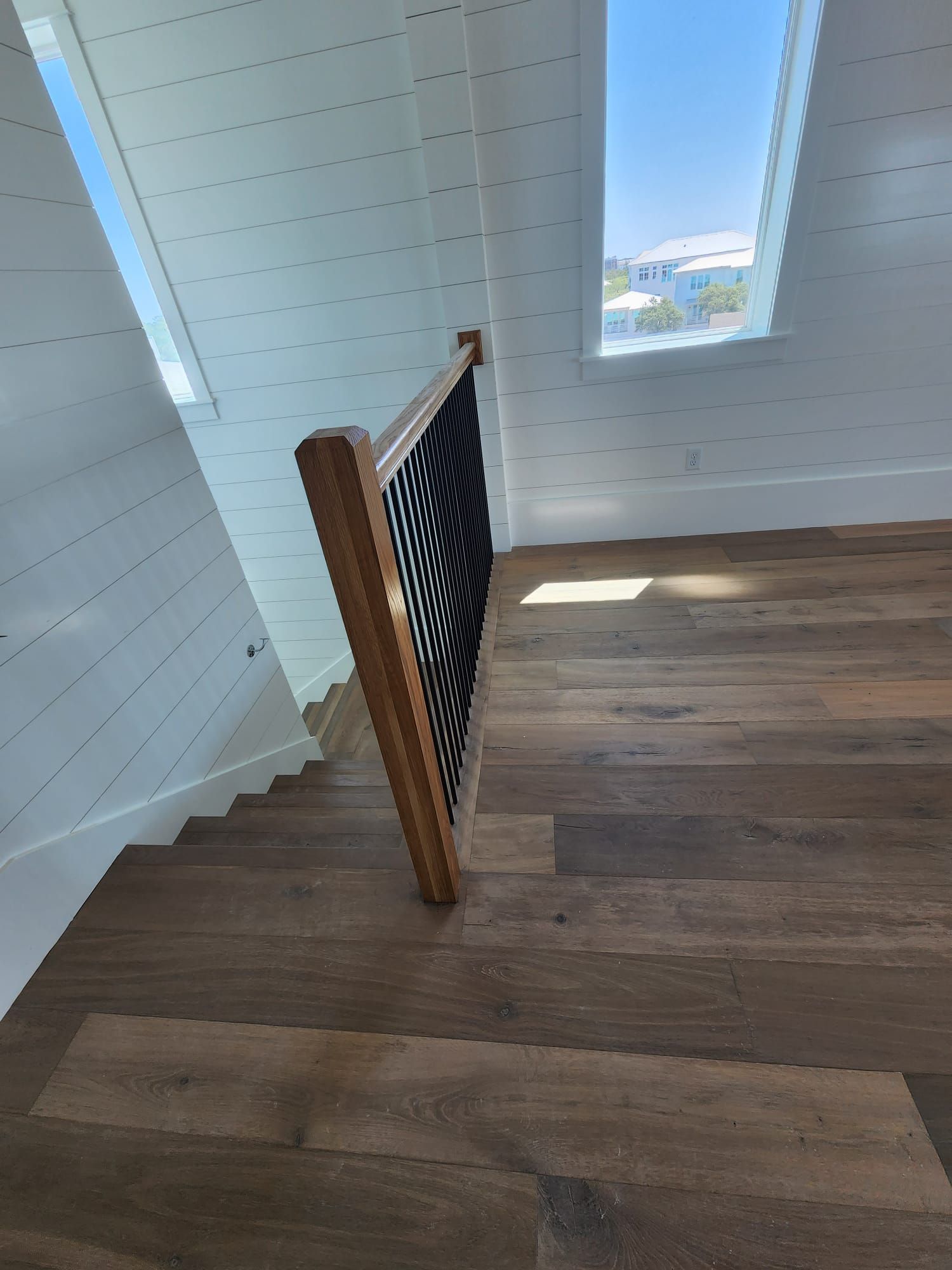 a wooden staircase with a black railing and a window