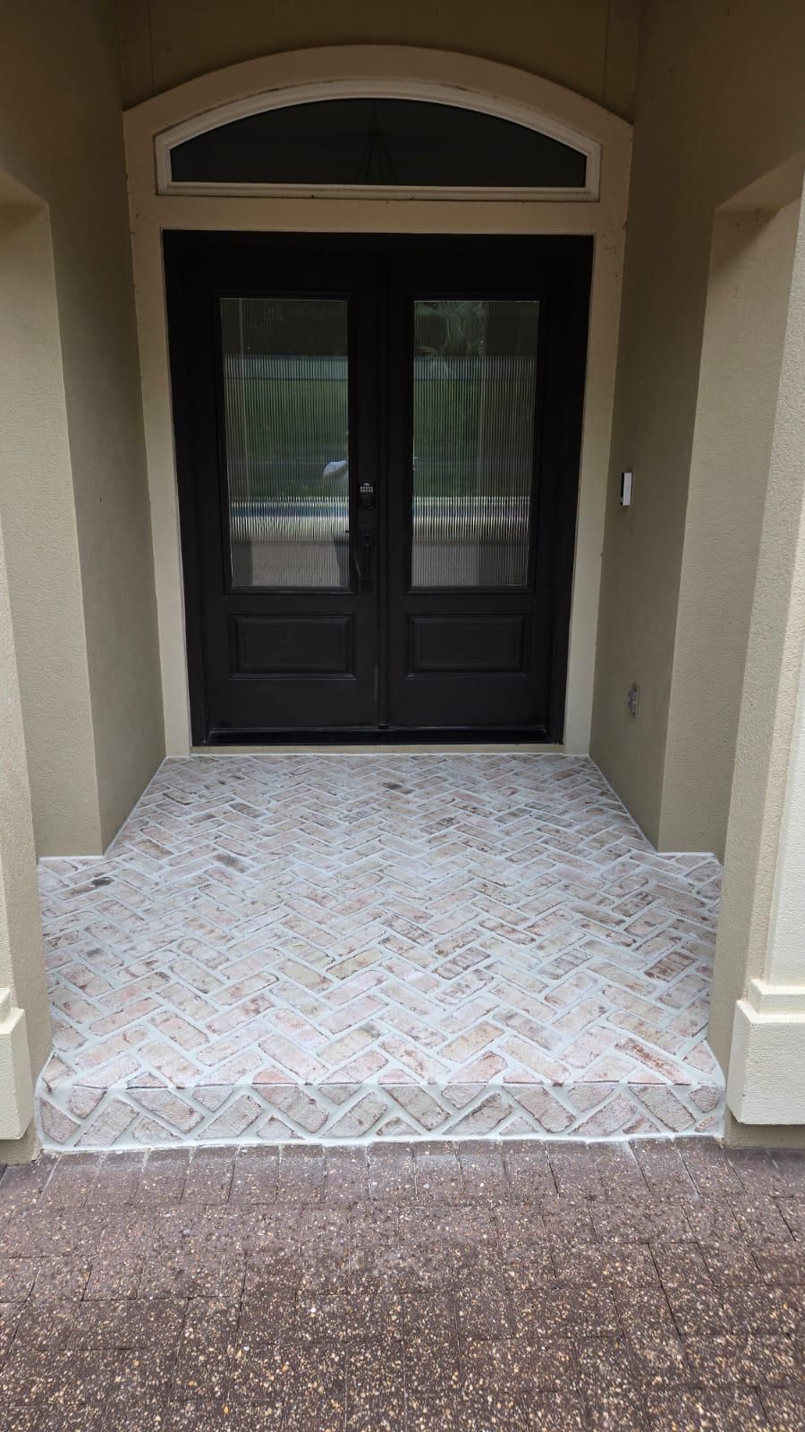 Front entry with double doors, arched top, and patterned concrete floor.