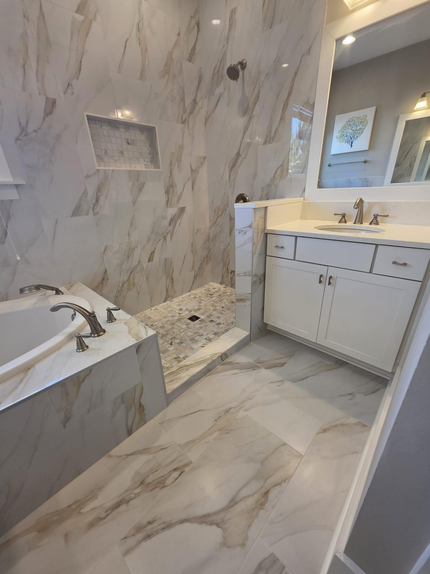 Marble-tiled bathroom with a shower, bathtub, vanity, and a large mirror.