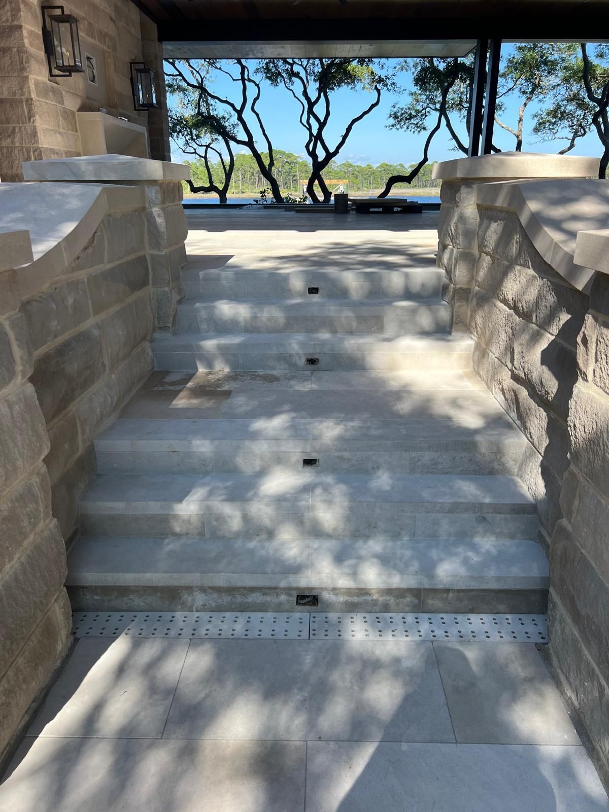 Stone steps leading up to an open view of water and trees, flanked by stone walls.