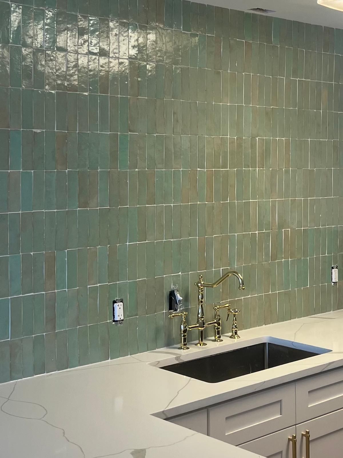 Green tile backsplash with a sink and faucet.