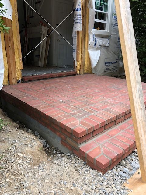 A brick porch is being built in front of a house.