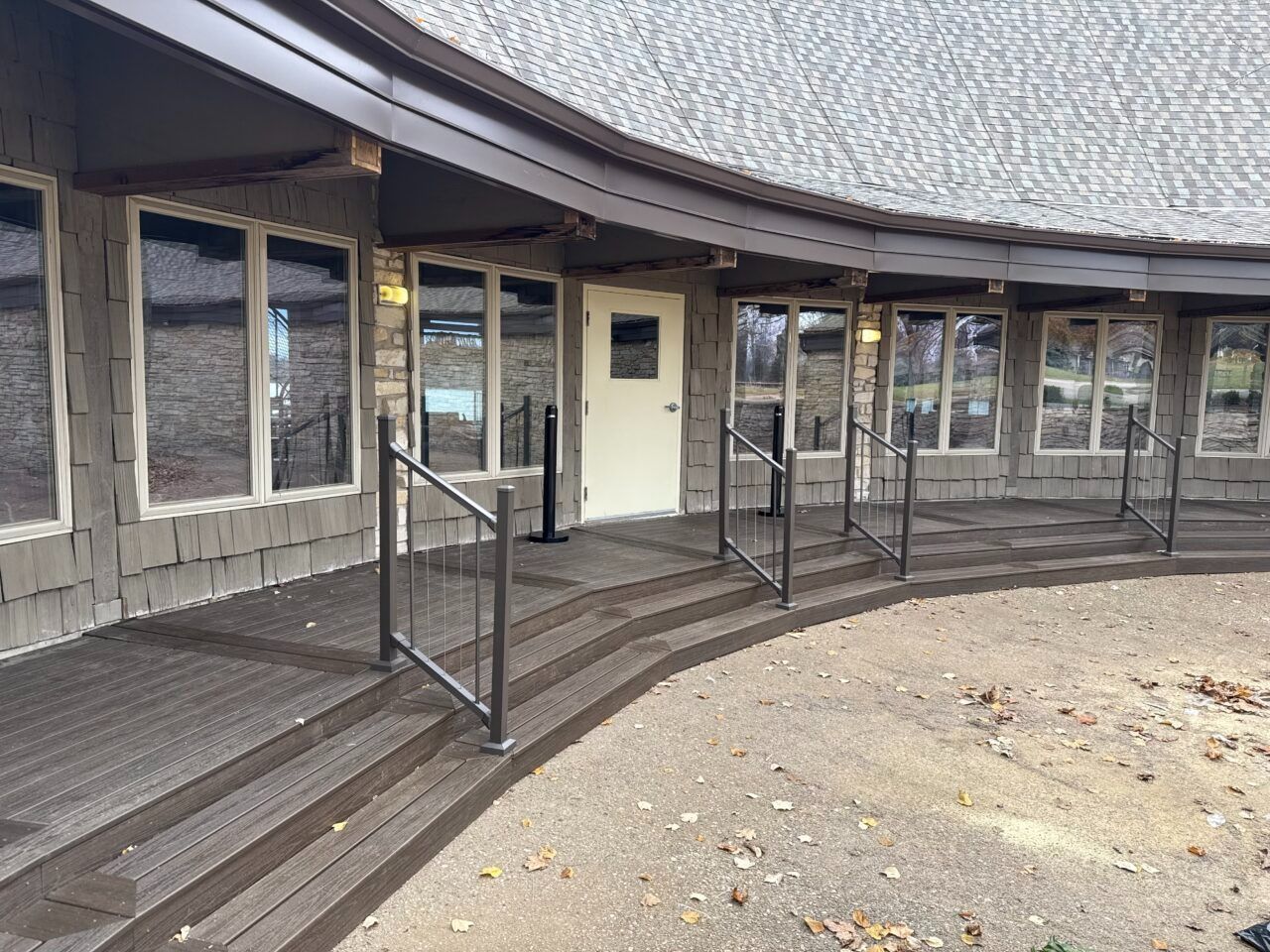 Curved building entrance with steps, ramp, and glass windows under a sloped roof