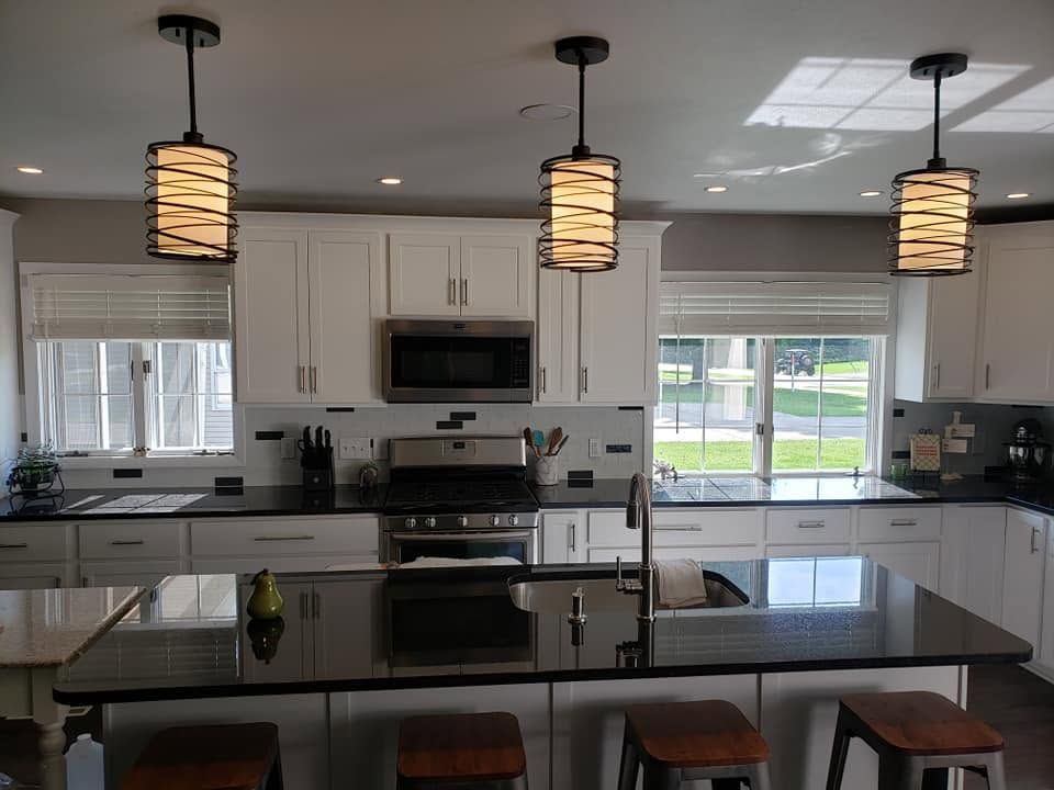Modern kitchen with island, pendant lights, white cabinets, and stainless steel appliances