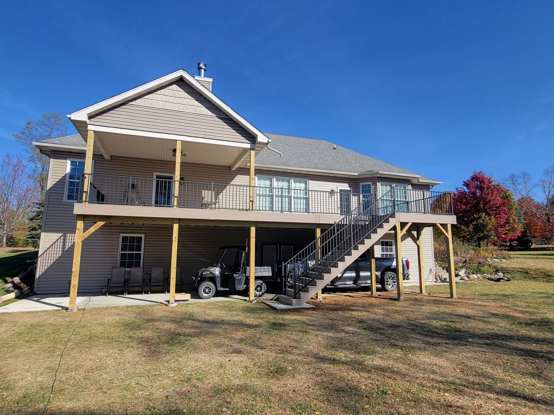House with a raised wooden deck and exterior stairs on a sunny day