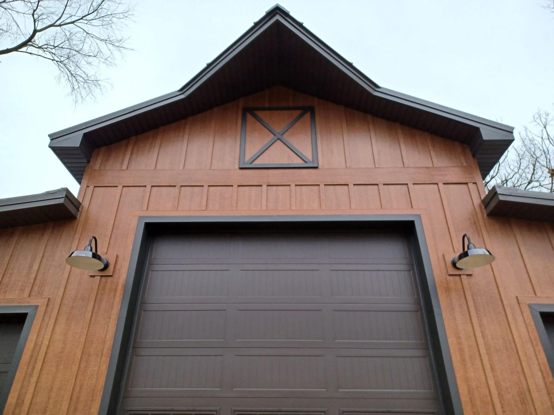 Wood-paneled barn-style garage with a dark brown door and black trim, viewed from below
