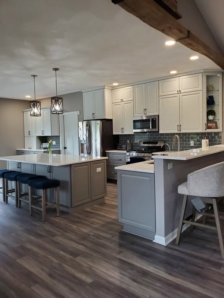 Modern open-concept kitchen with white cabinets, gray island, pendant lights, and dark wood flooring