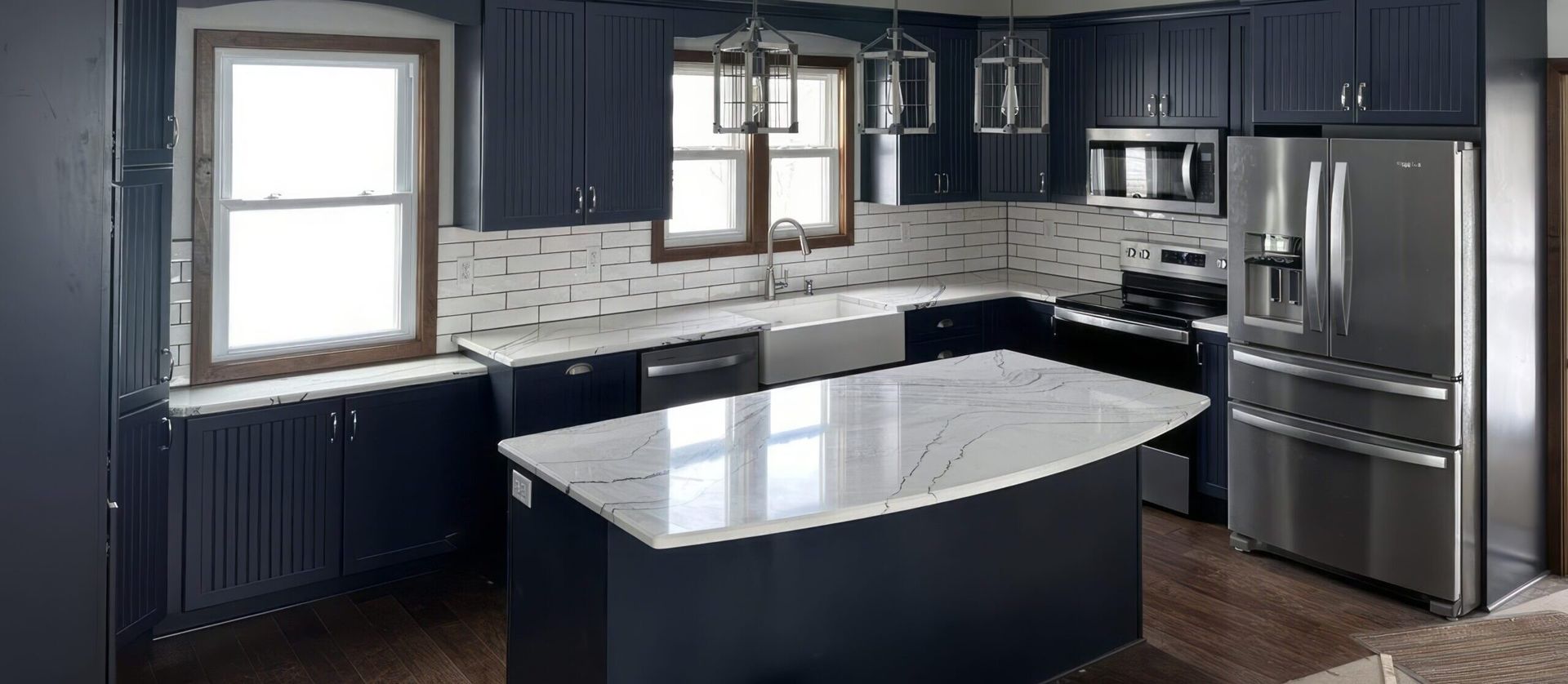 Modern kitchen with dark cabinets, stainless appliances, and a light-colored island countertop
