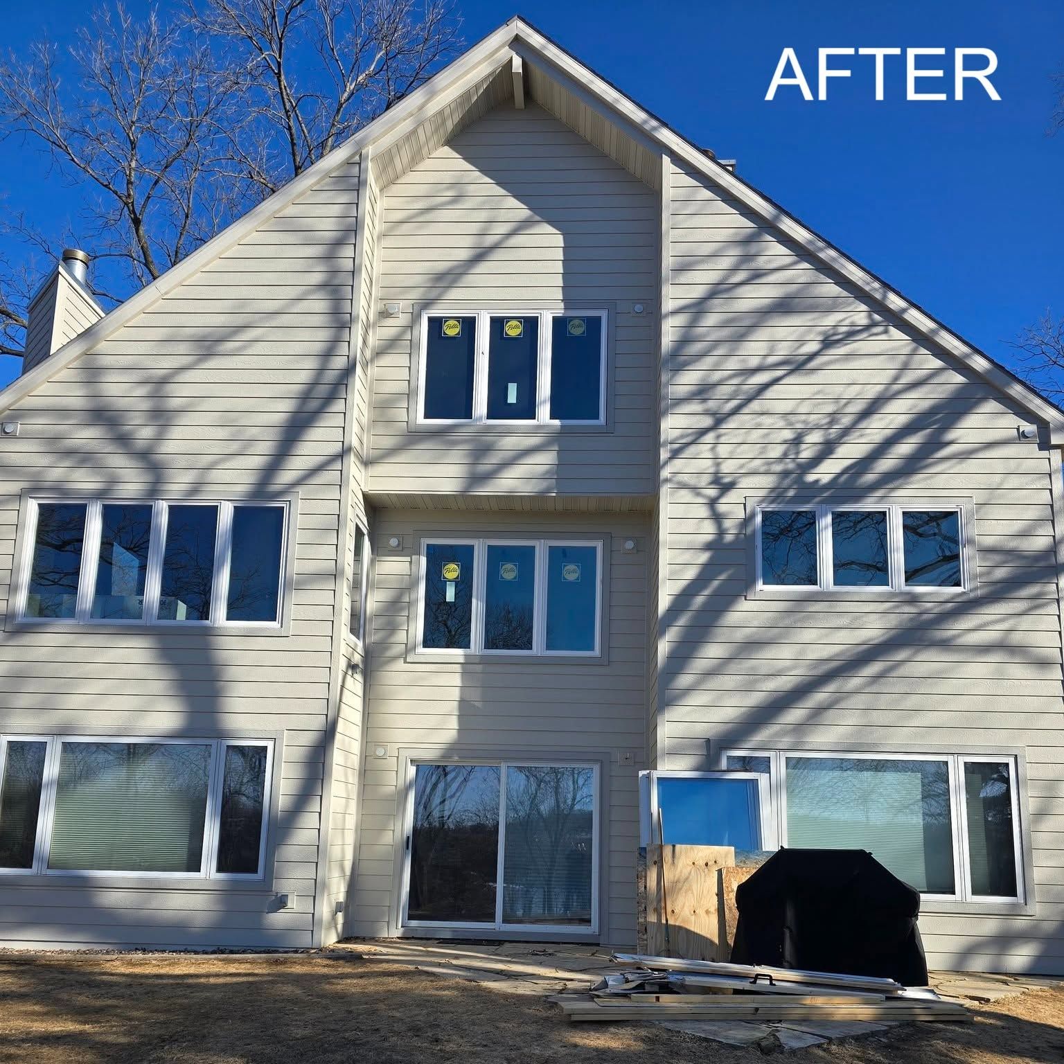 House exterior with new beige siding and windows under a blue sky, labeled “AFTER”