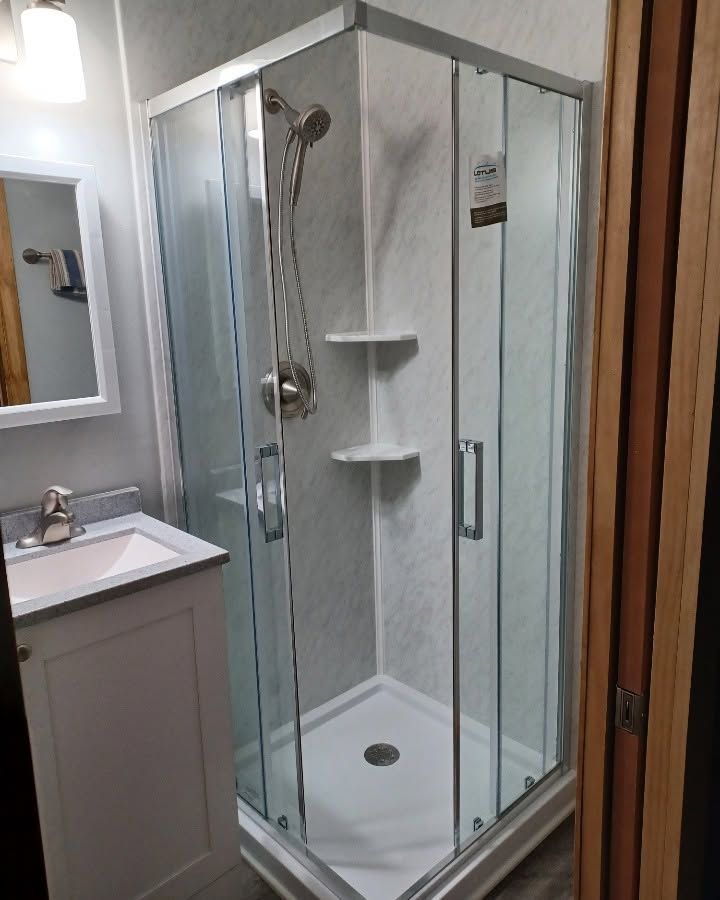Corner shower stall with glass doors and white tile in a bathroom